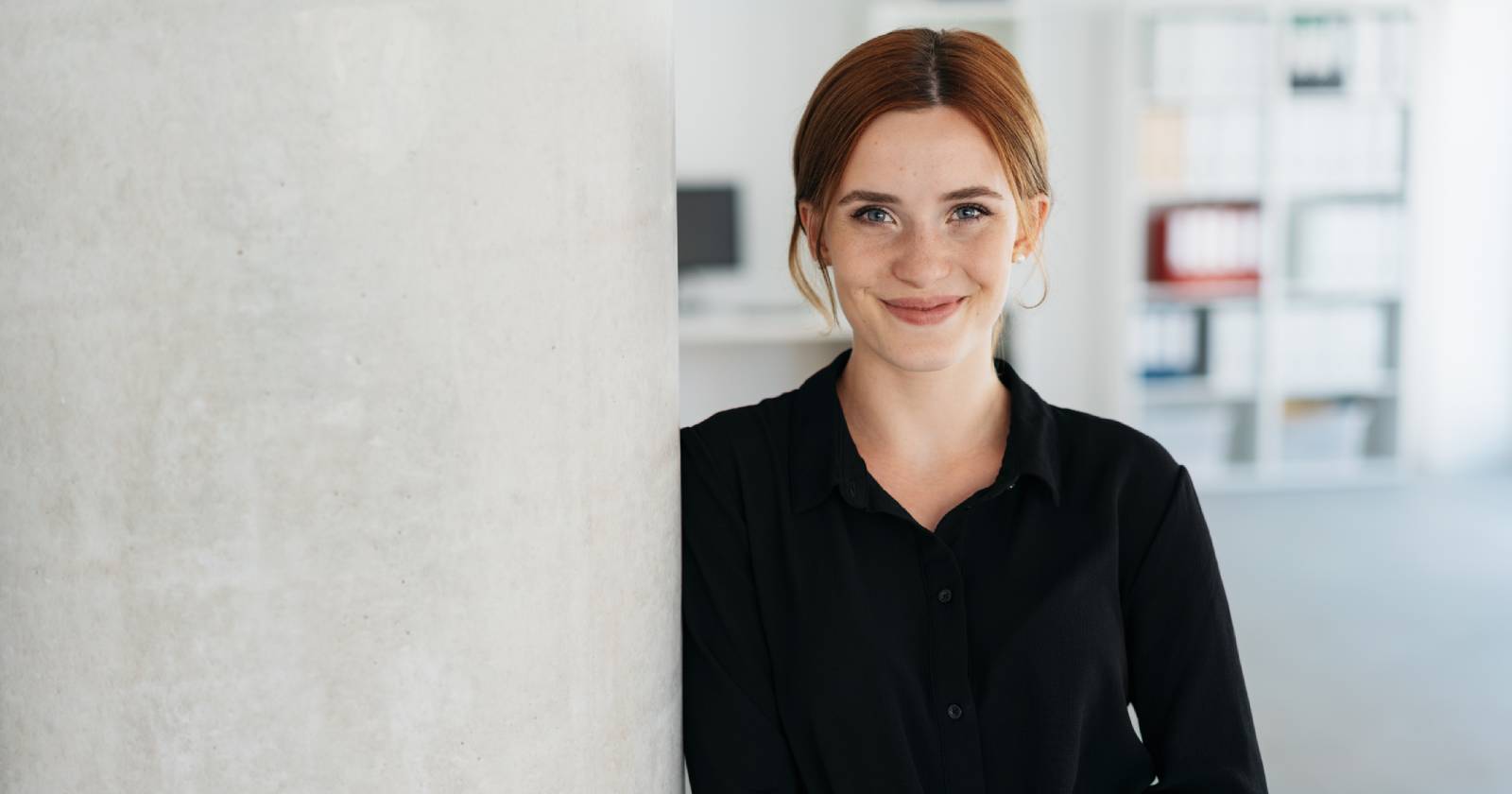 Junge zufriedene Frau lehnt an der Mauer | Credit: iStock.com/stockfour