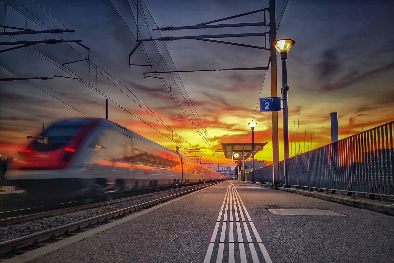 Zug passiert Bahnhof in der Abenddämmerung | Credit: iStock.com/Photosely