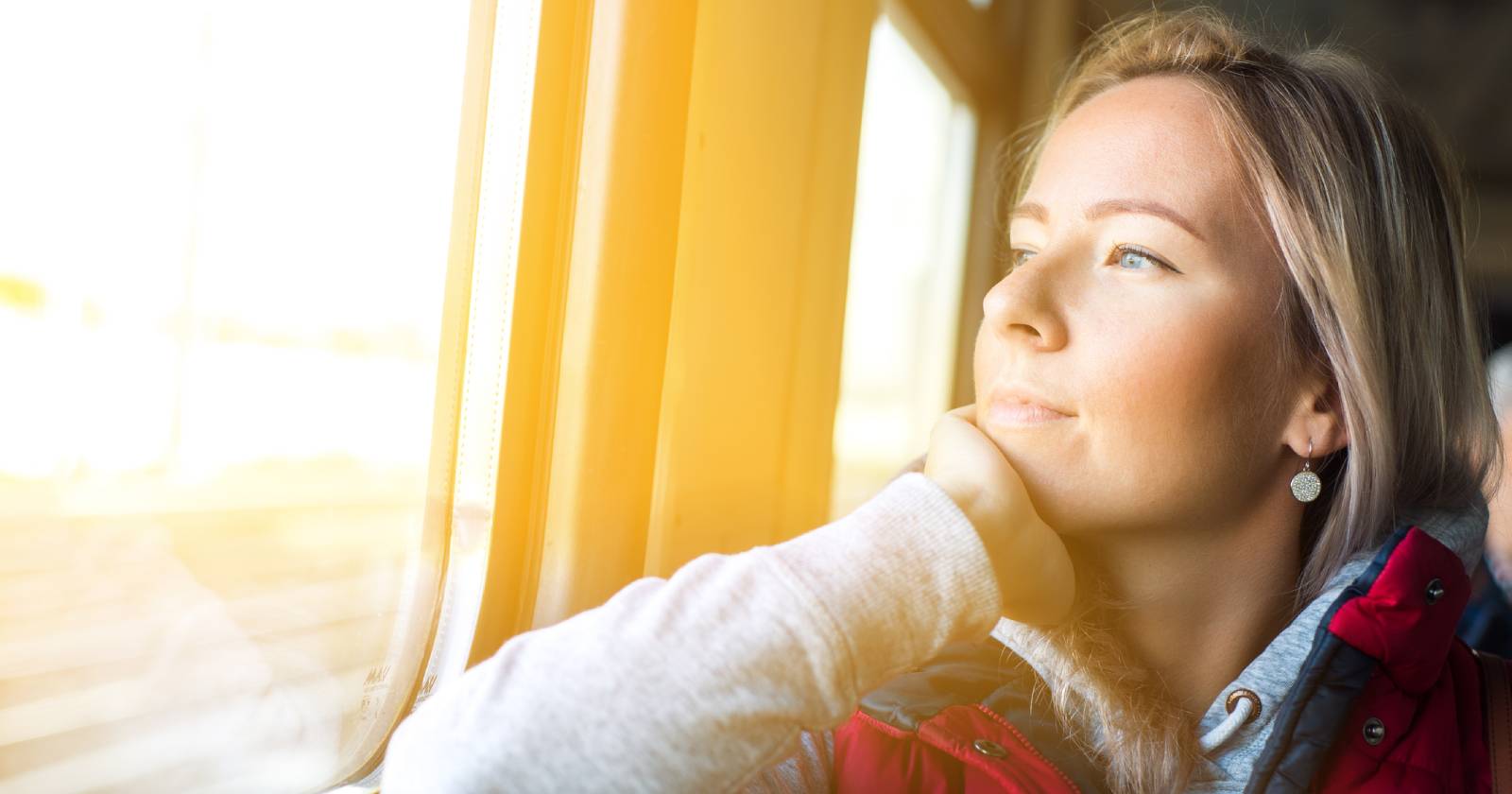 Frau blickt während der Zugfahrt aus dem Fenster | Credit: iStock.com/ALFSnaiper