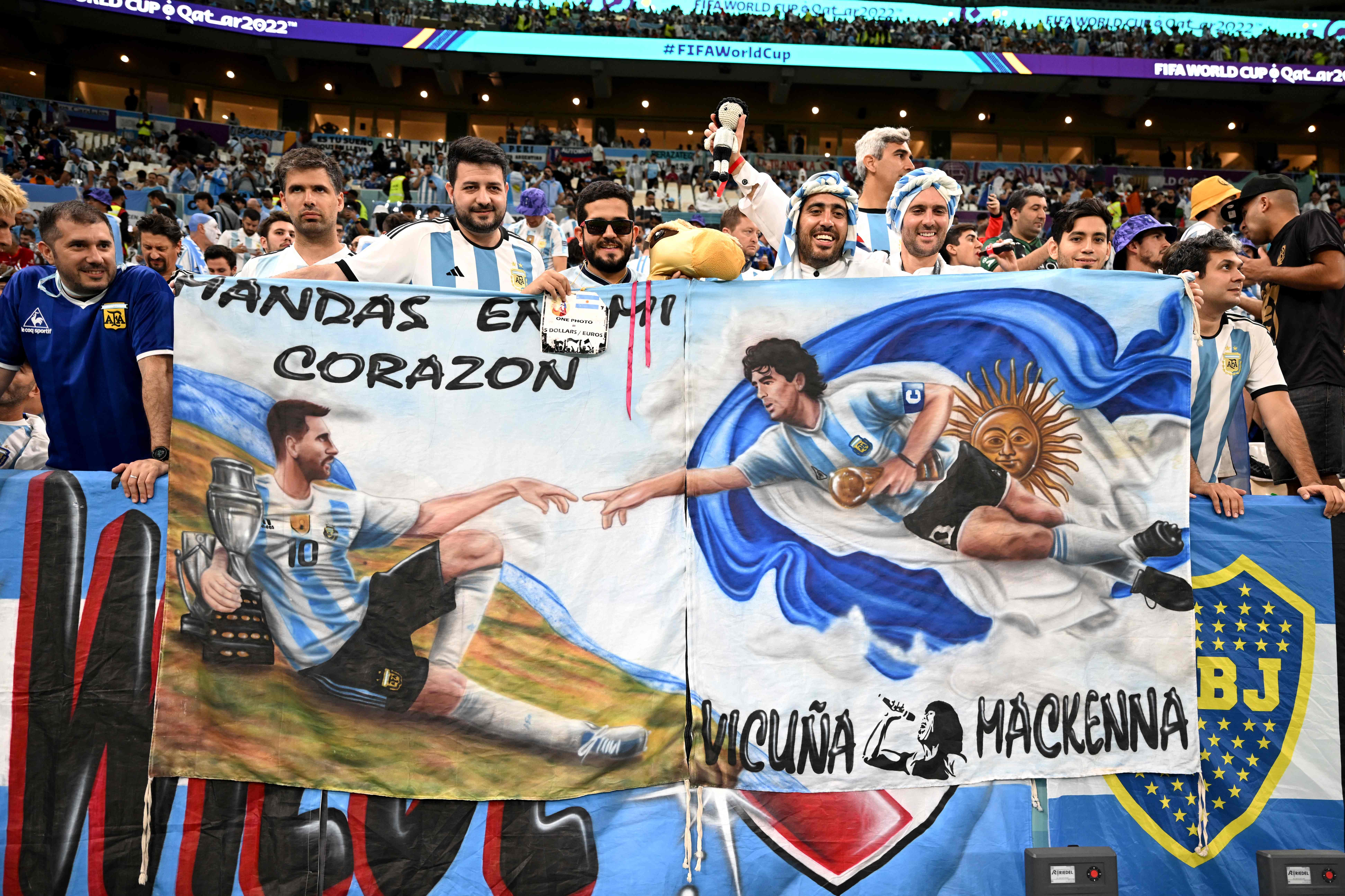 Argentinische Fans halten ein Plakat auf dem Messi und Maradona zu sehen sind.
