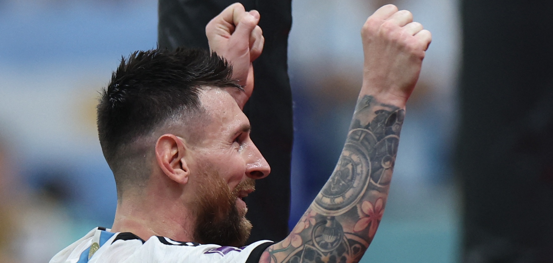 Lionel Messi mit hochgehobenen Armen im Seitenprofil.