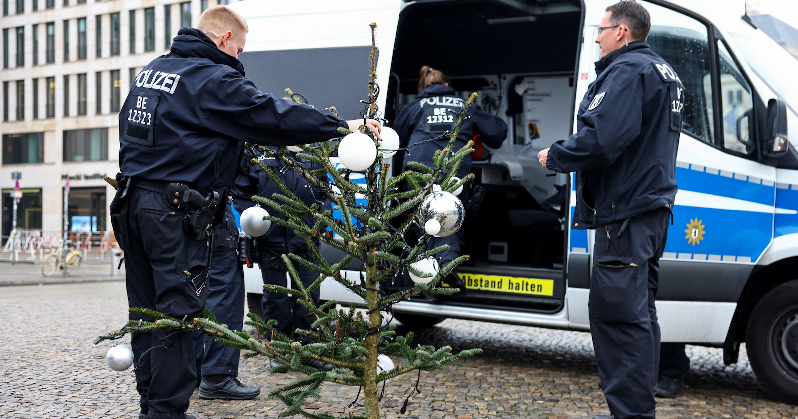 Zwei Polizisten mit Baumspitze vor Einsatzwagen