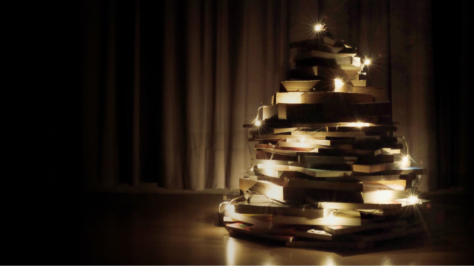 Ein Weihnachtsbaum aus Büchern steht im Wohnzimmer | Credit: iStock.com/Pimchada Silpee