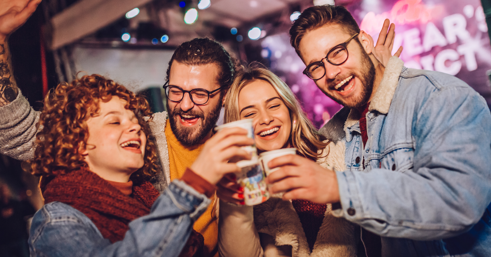 Freunde stoßen an einem Stand mit Glühwein an | Credit: iStock.com/Mina3686