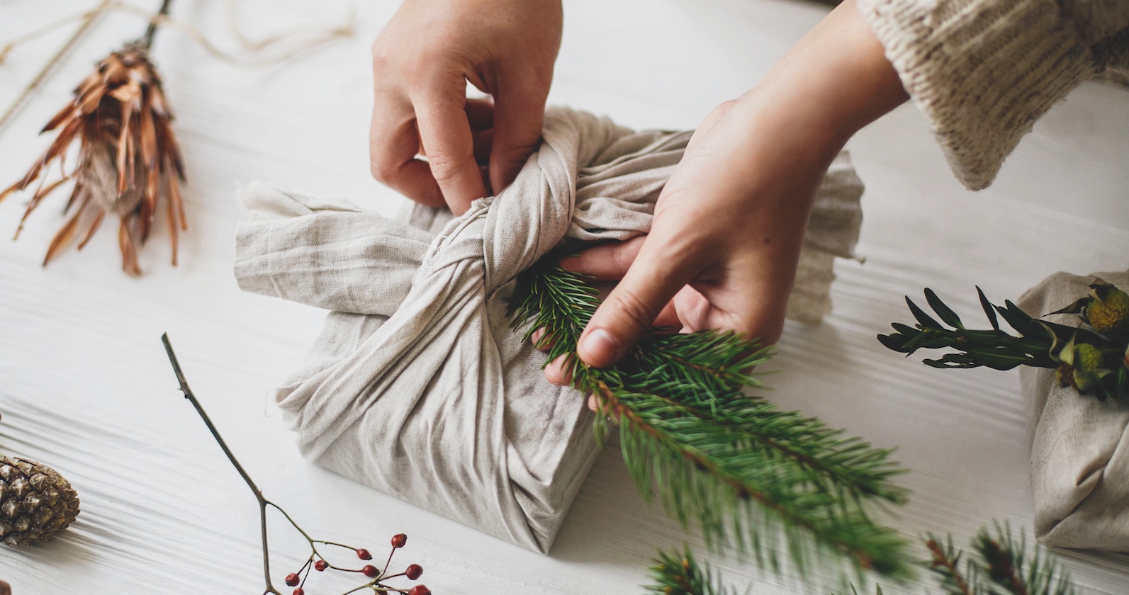 Frau bastelt Geschenk mit Tannenzweig. | Credit: iStock.com/Bogdan Kurylo