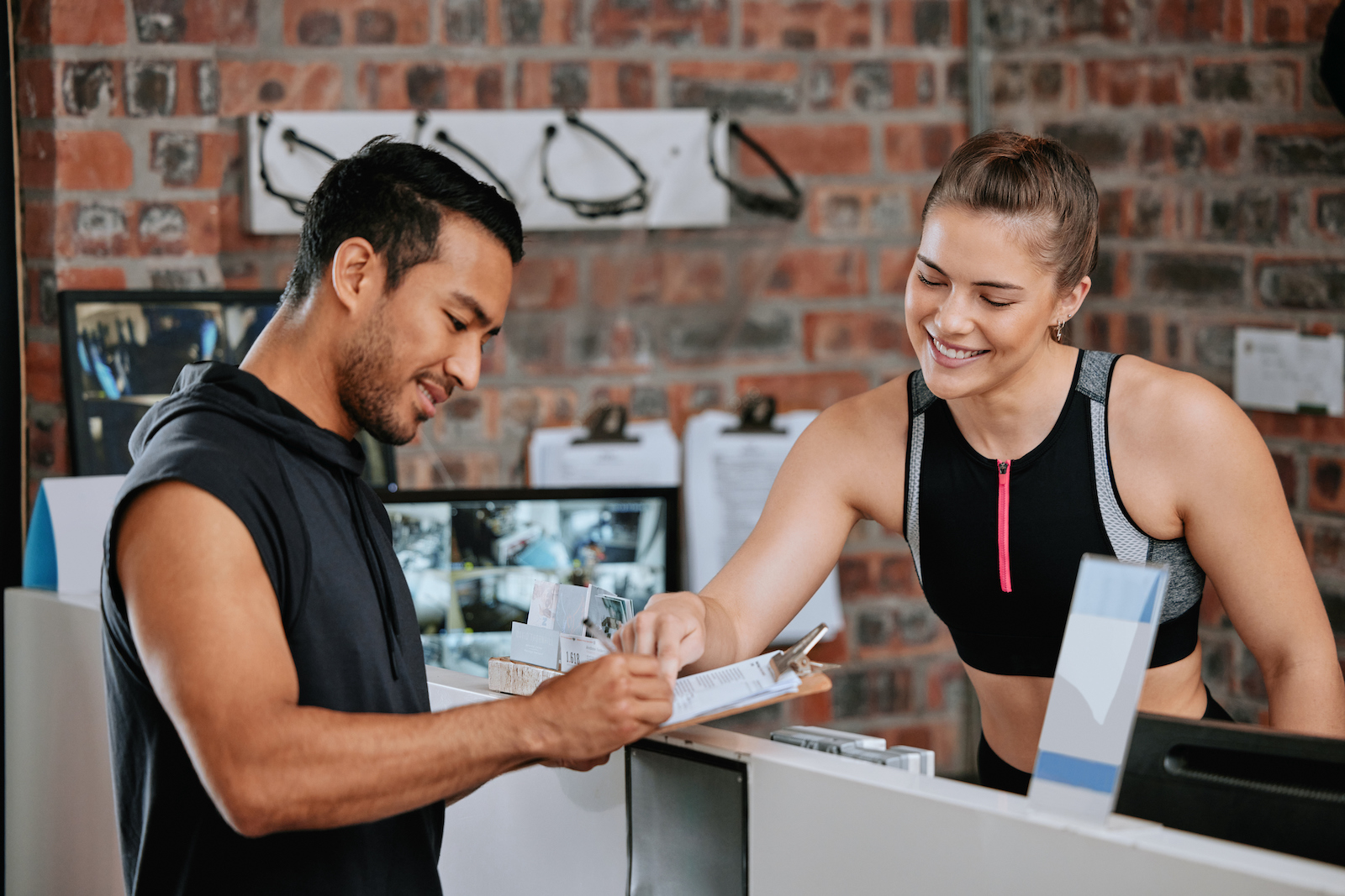 Mann und Frau bei einem Vertragsabschluss in einem Fitnessstudio. | Credit: iStock.com/PeopleImages