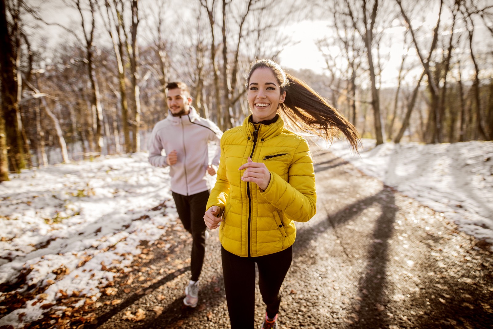 Frau und Mann laufen im Winter durch den Wald | Credit: iStock.com/dusanpetkovic