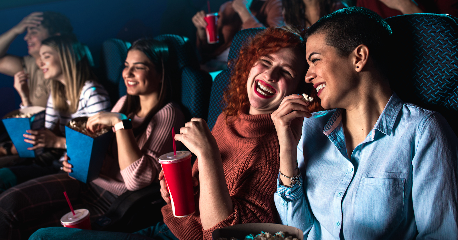lachende Menschen essen Popcorn im Kino | Credit: iStock.com/Zoran Zeremski