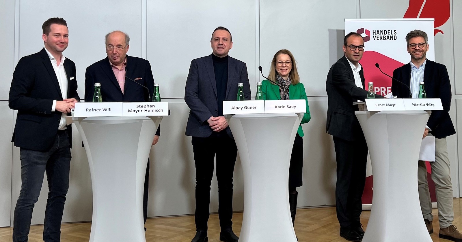 Stehend hinter Tischen mit Namensschildern