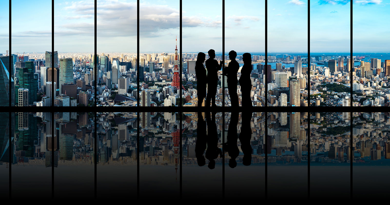 Geschäftsleute in einem Hochhaus mit Blick auf die Skyline von Tokio | Credit: iStock.com/metamorworks