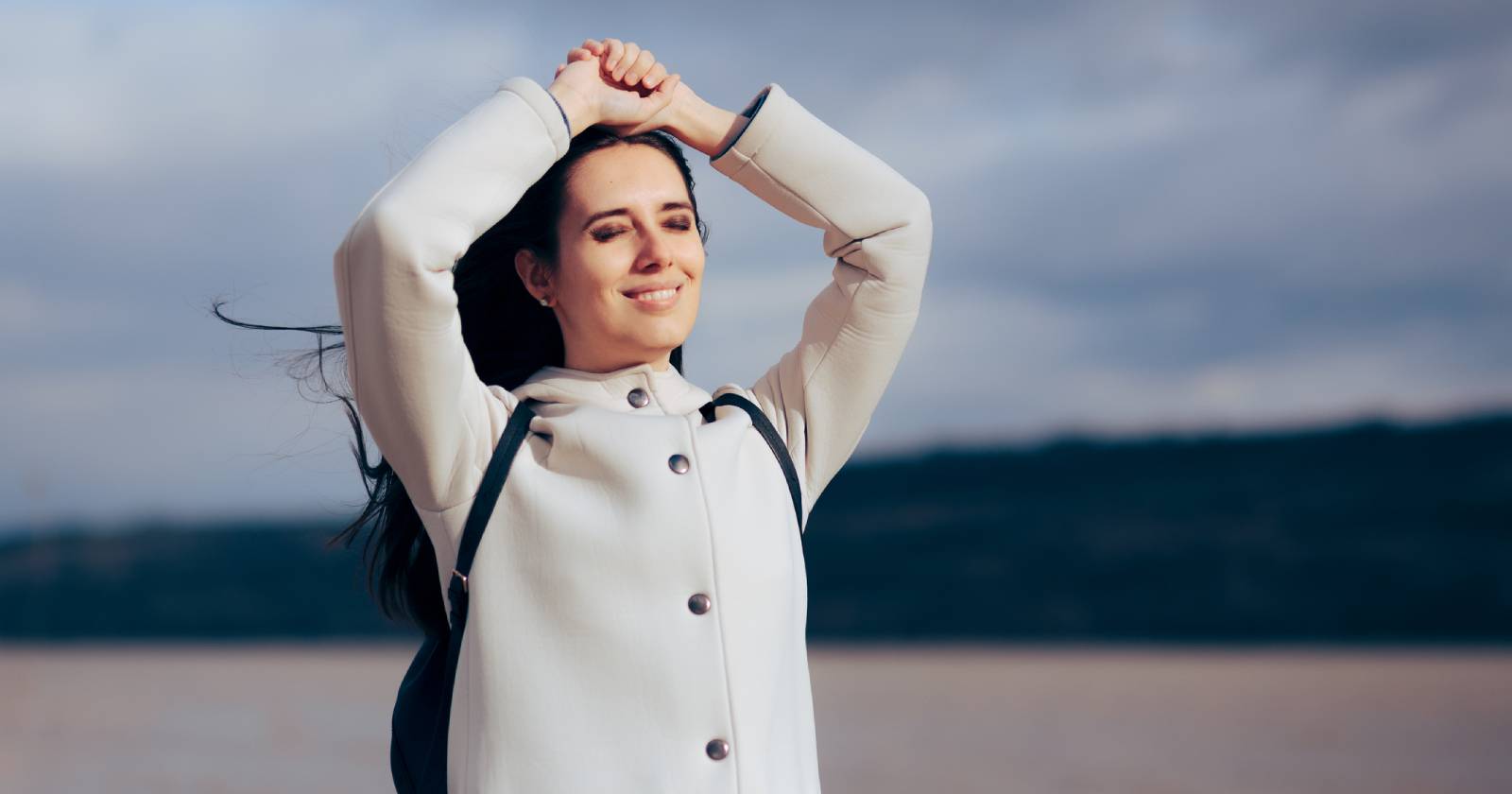 Junge Frau genießt die Sonne bei einem Winterspaziergang | Credit: iStock.com/nicoletaionescu