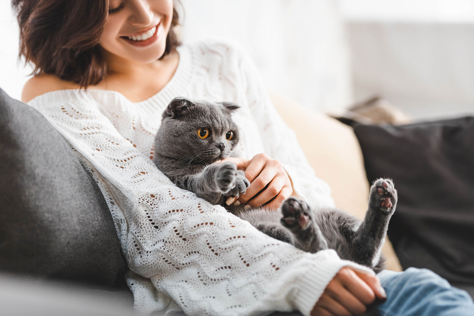 Junge Katze mit ihrer Katze auf der Couch | Credit: iStock.com/LightFieldStudios