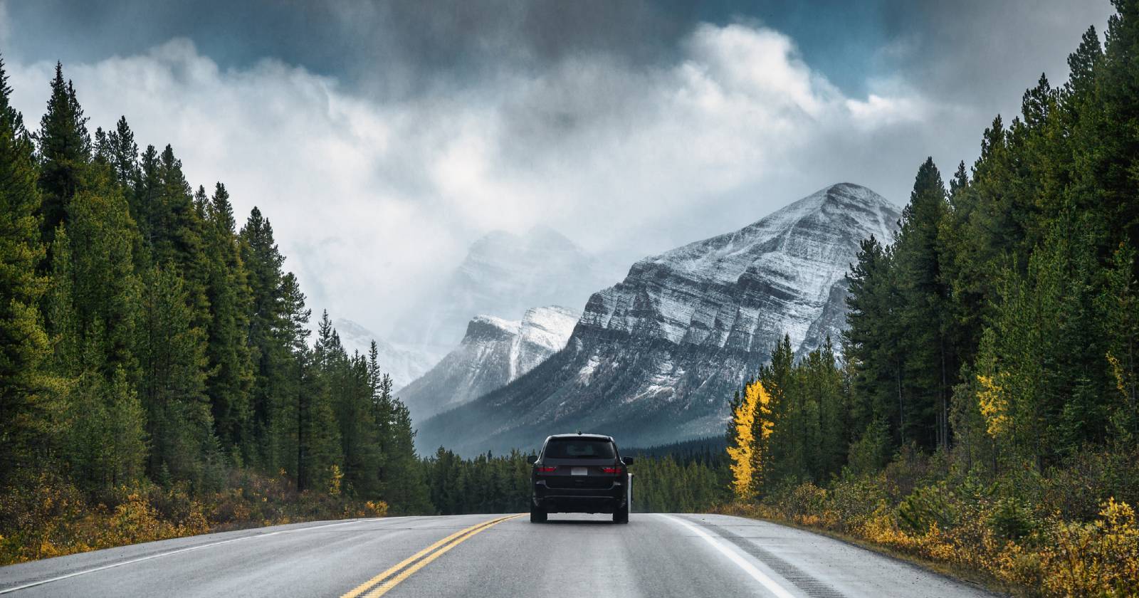 SUV unterwegs auf einsamer Landstraße an einem wolkenverhangenen Tag | Credit: iStock.com/Rustic Wanderlust