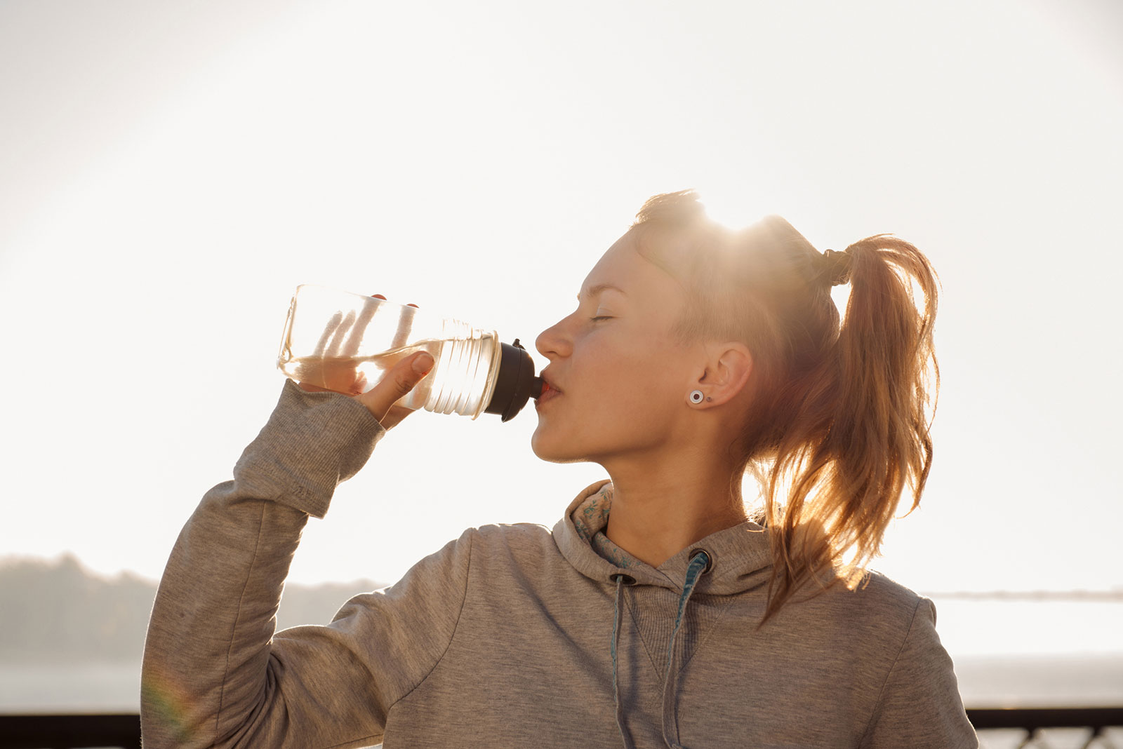 Frau trinkt in ihrer Trainingspause Wasser aus der Flasche | Credit: iStock.coM/Gilitukha