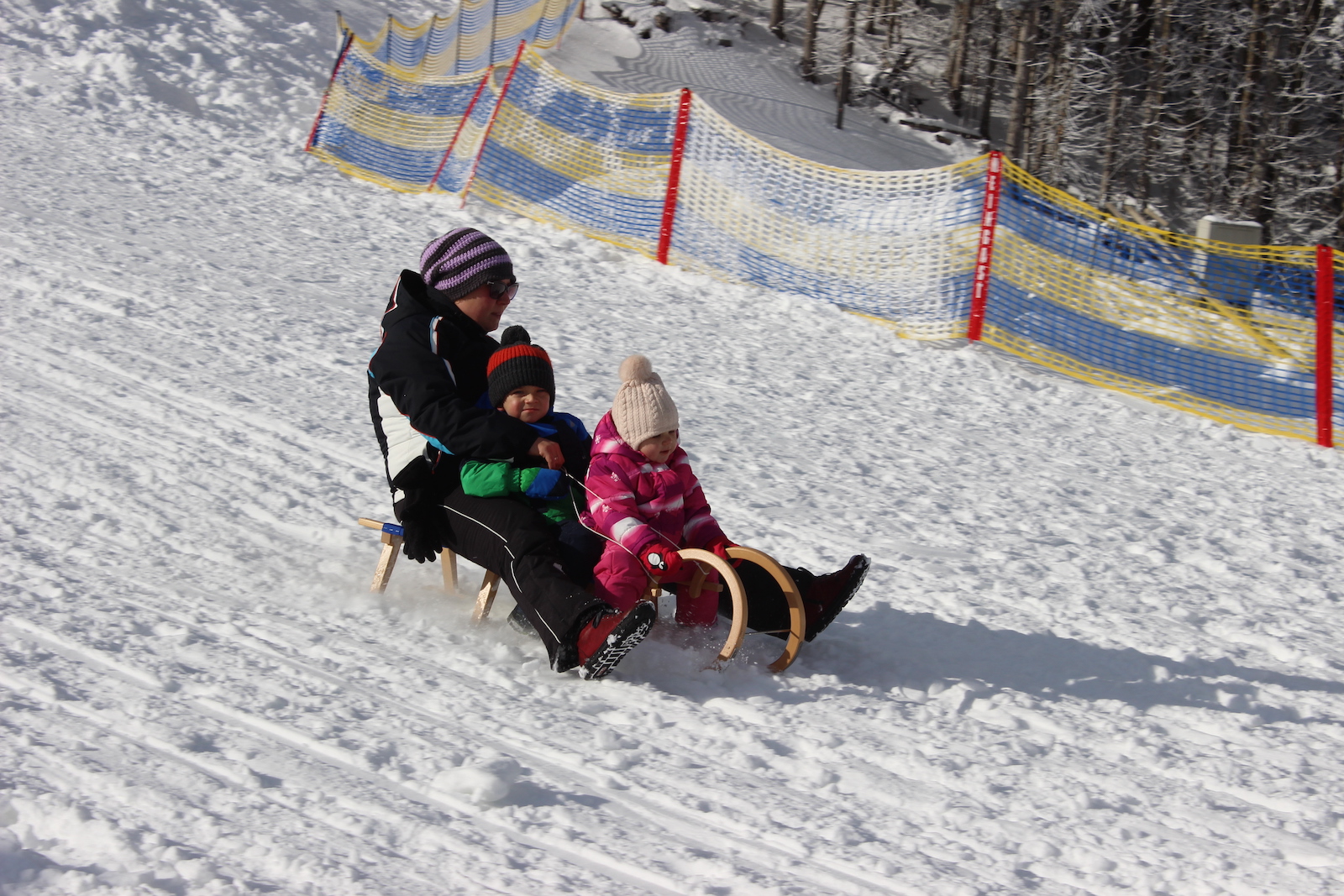 Drei Personen fahren mit einem Schlitten. Zwei davon Kinder, die vorne sitzen. | Credit: Erlebnisregion Oststeiermark / OTS