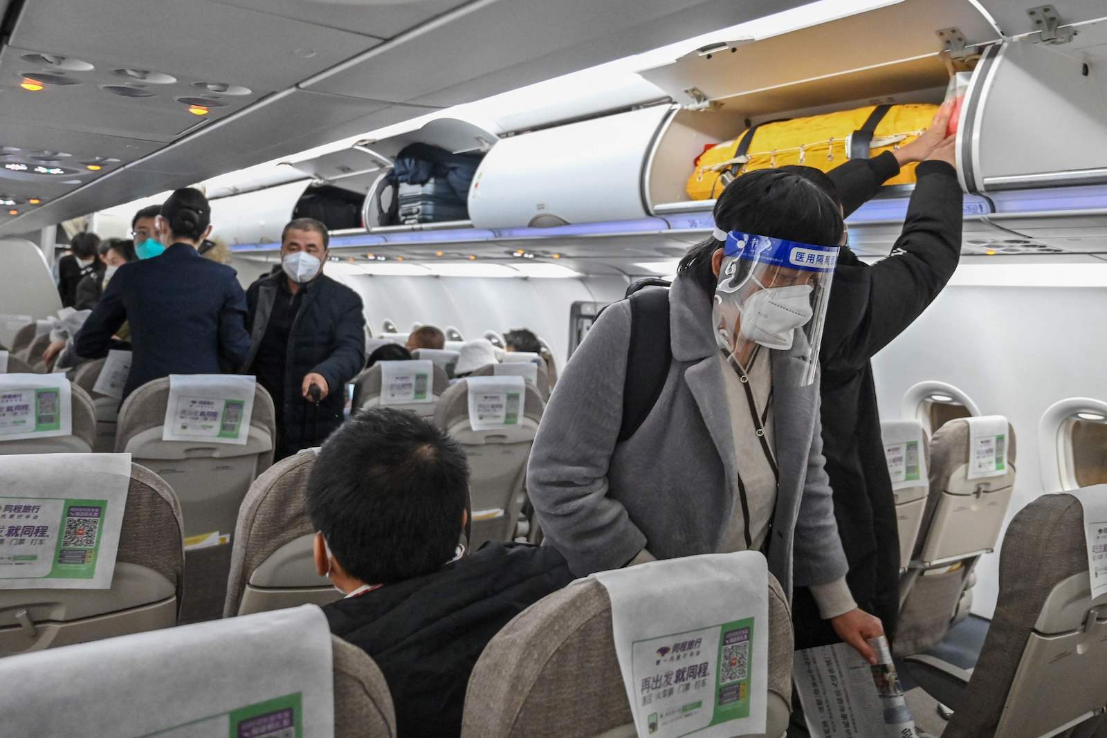 Asiatische Passagiere in einem Flugzeug. | Credit: HECTOR RETAMAL / AFP / picturedesk.com