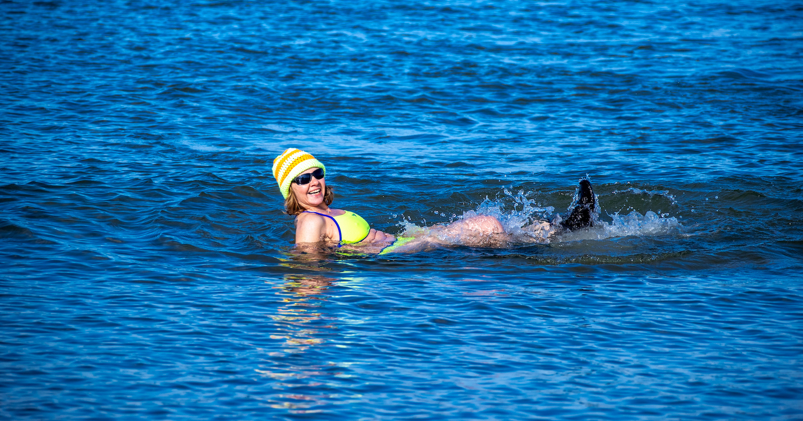 Frau badet mit gelber Haube im winterlichen See | Credit: Jens Büttner / dpa / picturedesk.com