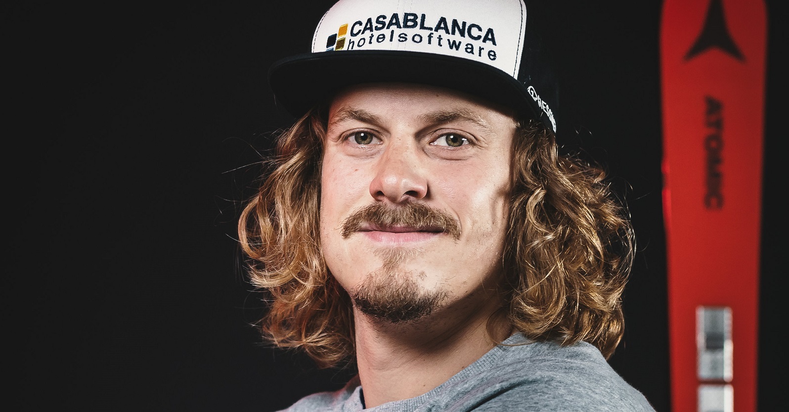 Porträtfoto von Manuel Feller mit seinem Ski im Hintergrund