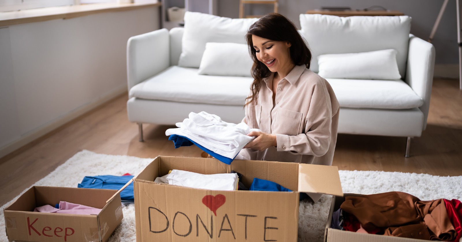 Frau sitzt in der Mitte von Kisten und ordnet ihr Zuhause | Credit: iStock.com/AndreyPopov