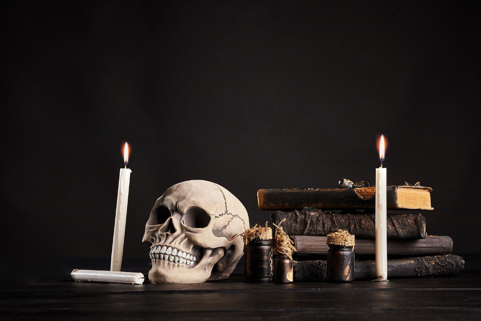 Totenkopf steht mit Kerzen auf einem schwarzen Tisch | Credit: iStock.com/Sergey Nazarov