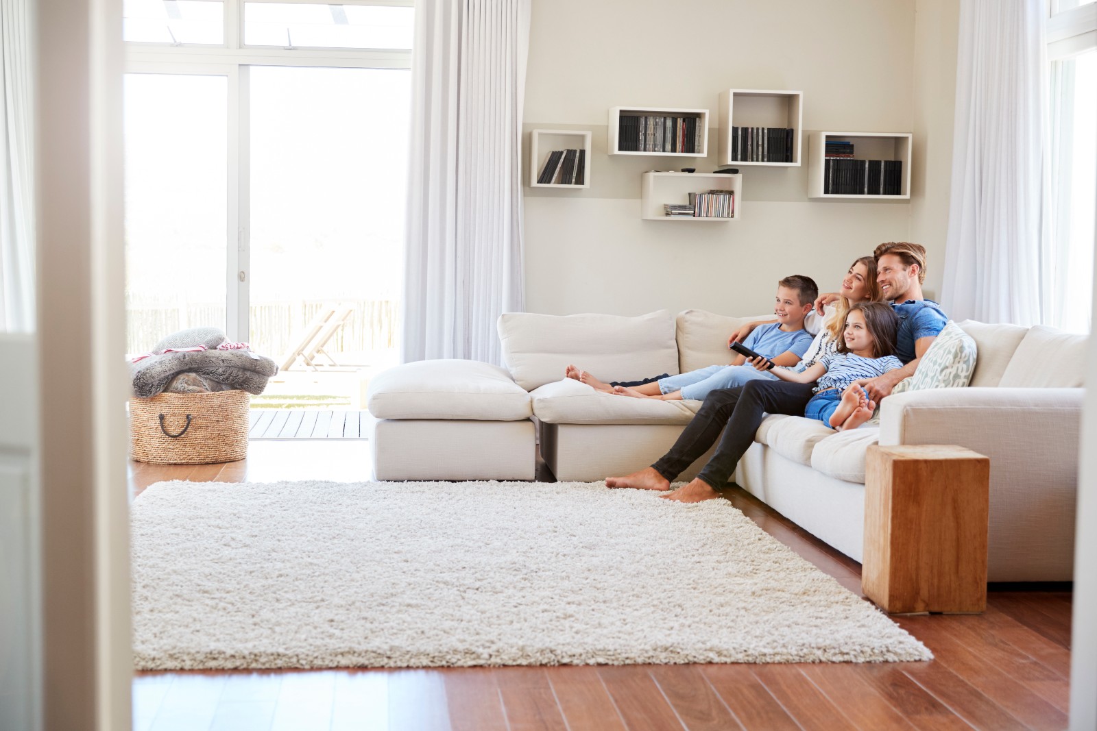 Familie sitzt im Wohnzimmer auf der Couch | Credit: iStock.com/monkeybusinessimage