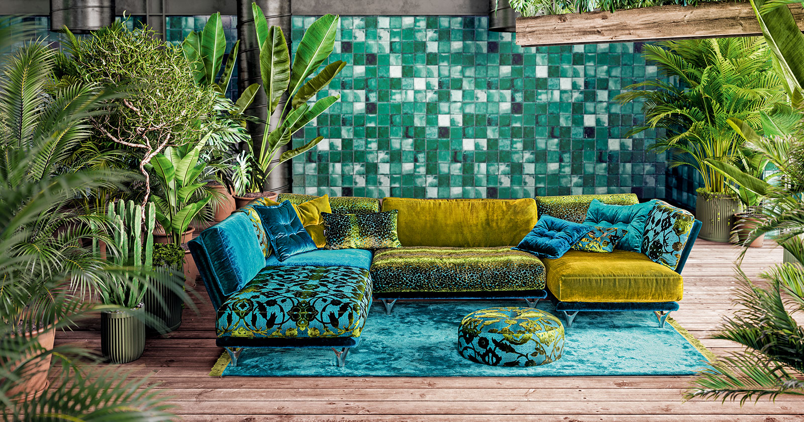 Ein Grün-Blaues Sofa steht vor einer grünen Wand | Credit: A.K.H. Möbel GmbH