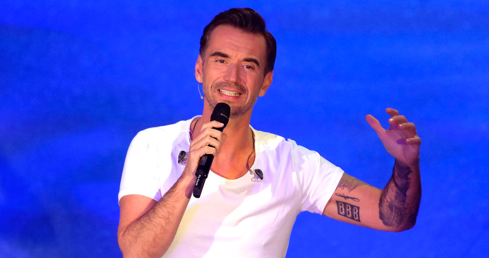 Florian Silbereisen hält ein Mikrofon und singt.