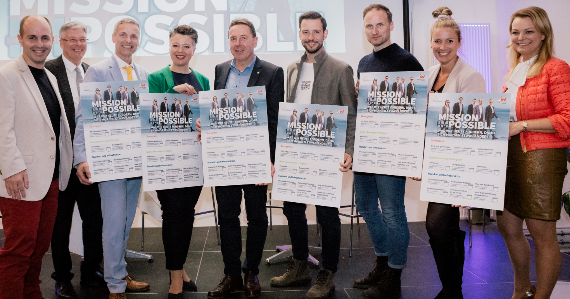 Vertreter der JW-Kärnten übergeben den Spitzenkandidaten der Parteien der kommenden Landtagswahl auf einer Diskussionsbühne jeweils eine überdimensionierte Forderungsliste