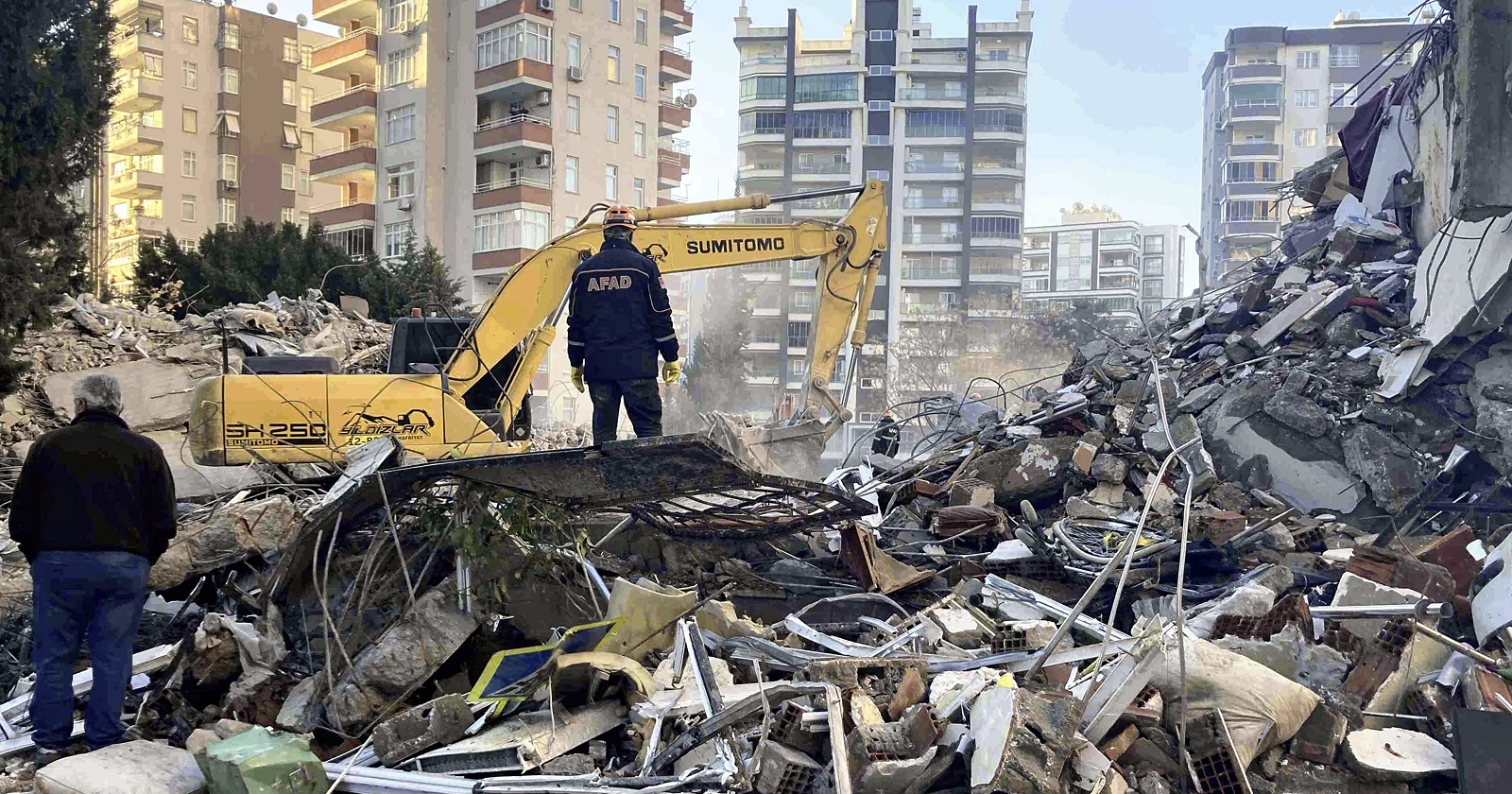 Ein Bagger und ein Mann stehen auf den Trümmern eines Hauses