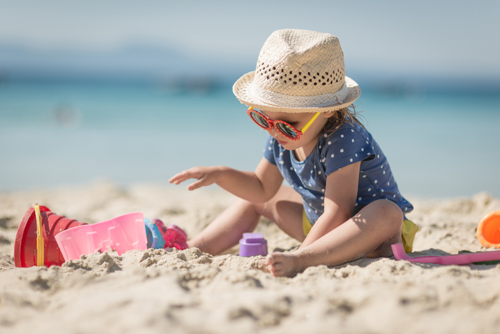 Kind spielt mit Sandspielsachen am Strand.
