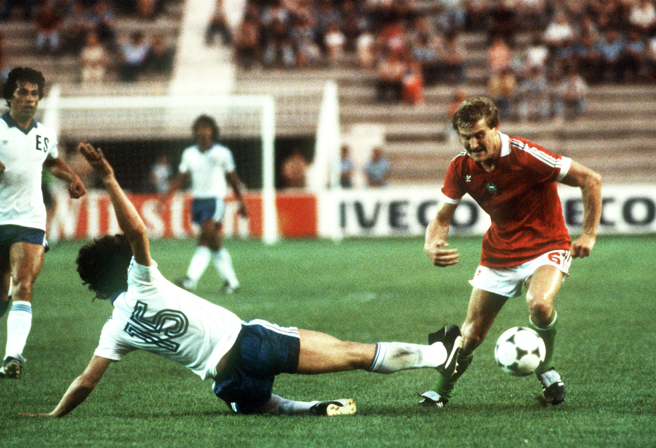 Ein ungarischer Fußballspieler lässt seinen herangrätschenden Gegenspieler aus El Salvador elegant ins Leere rutschen