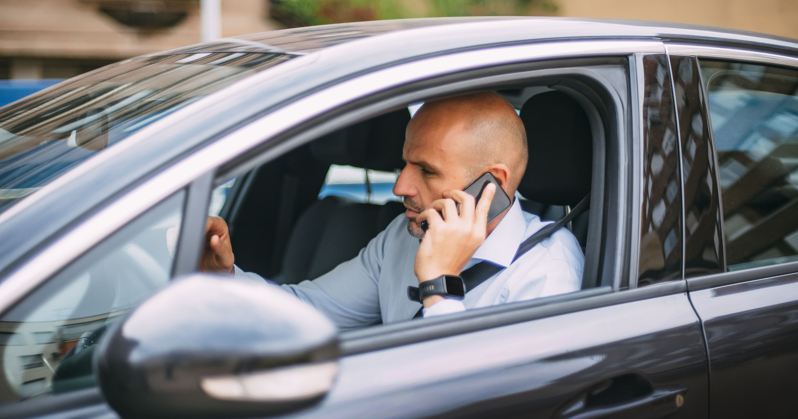 Mann telefoniert während des Autofahrens ohne Freisprechanlage.
