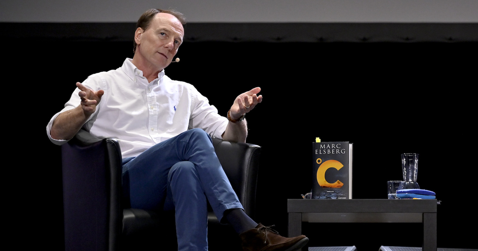 Autor Mark Elsberg sitzt auf einem schwarzen Sessel.