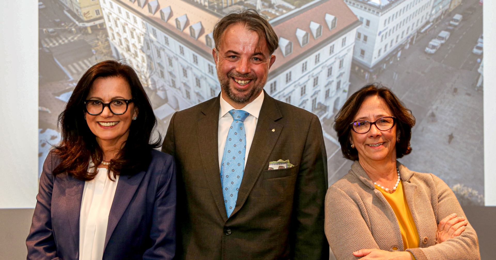 Die Vorstände der Kärntner Sparkasse vor einem auf die Rückwand projezierten Bild der Firmenzentrale