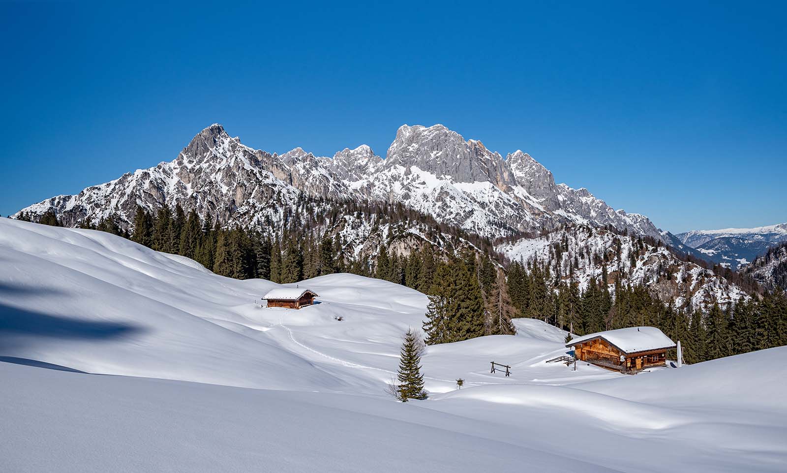 Zwei Berghütten im Schnee | Credit: iStock.com/auerimages