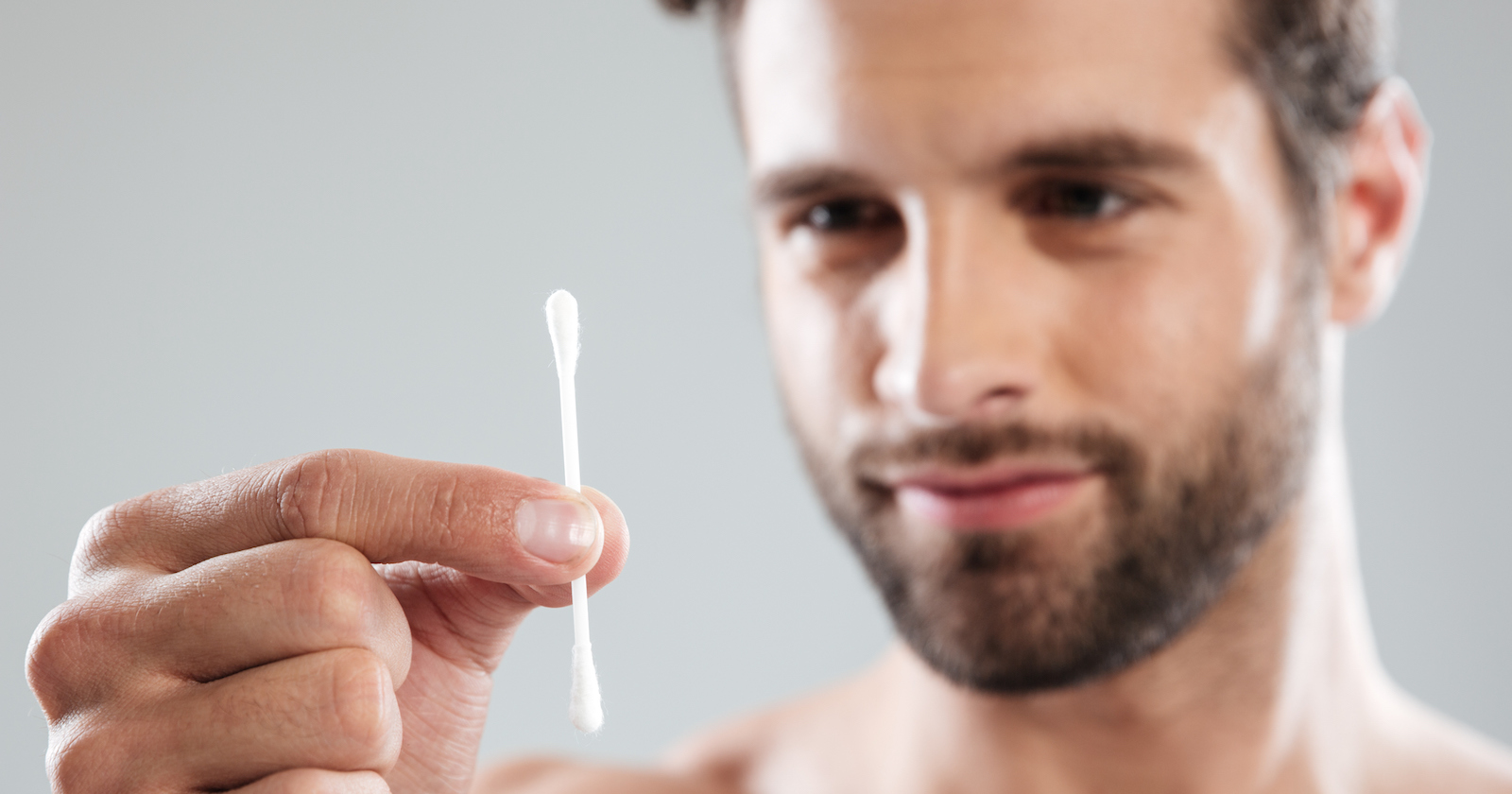 Mann hält eine Wattestäbchen in der Hand.