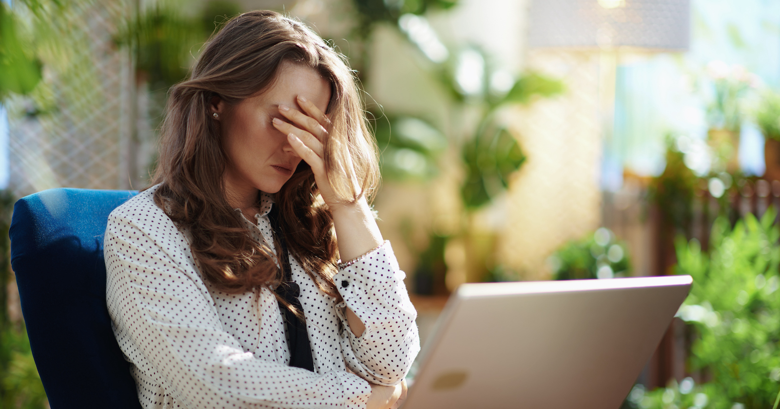 Frau sitzt müde vor dem Laptop.