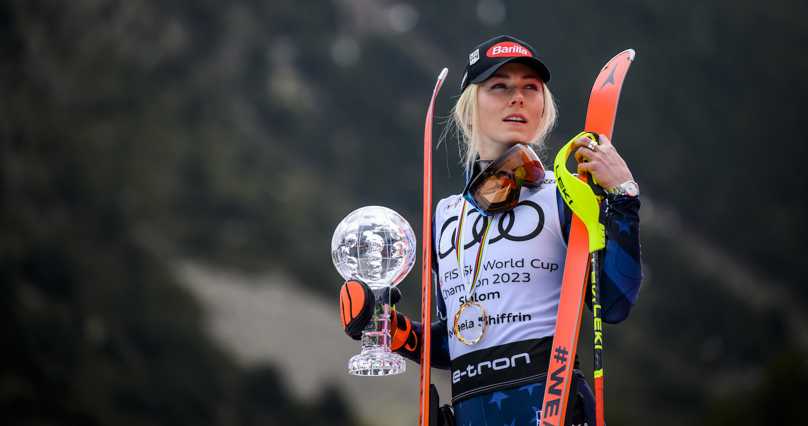 Mikaela Shiffrin mit Skiern und Weltcup-Kugel.