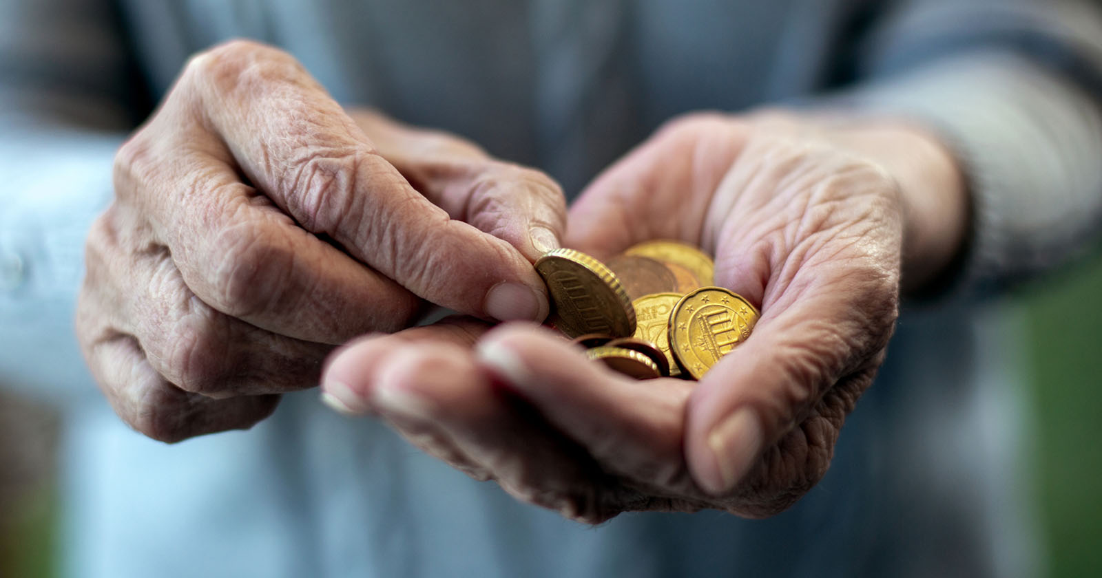Hände einer älteren Frau mit Euro-Münzen