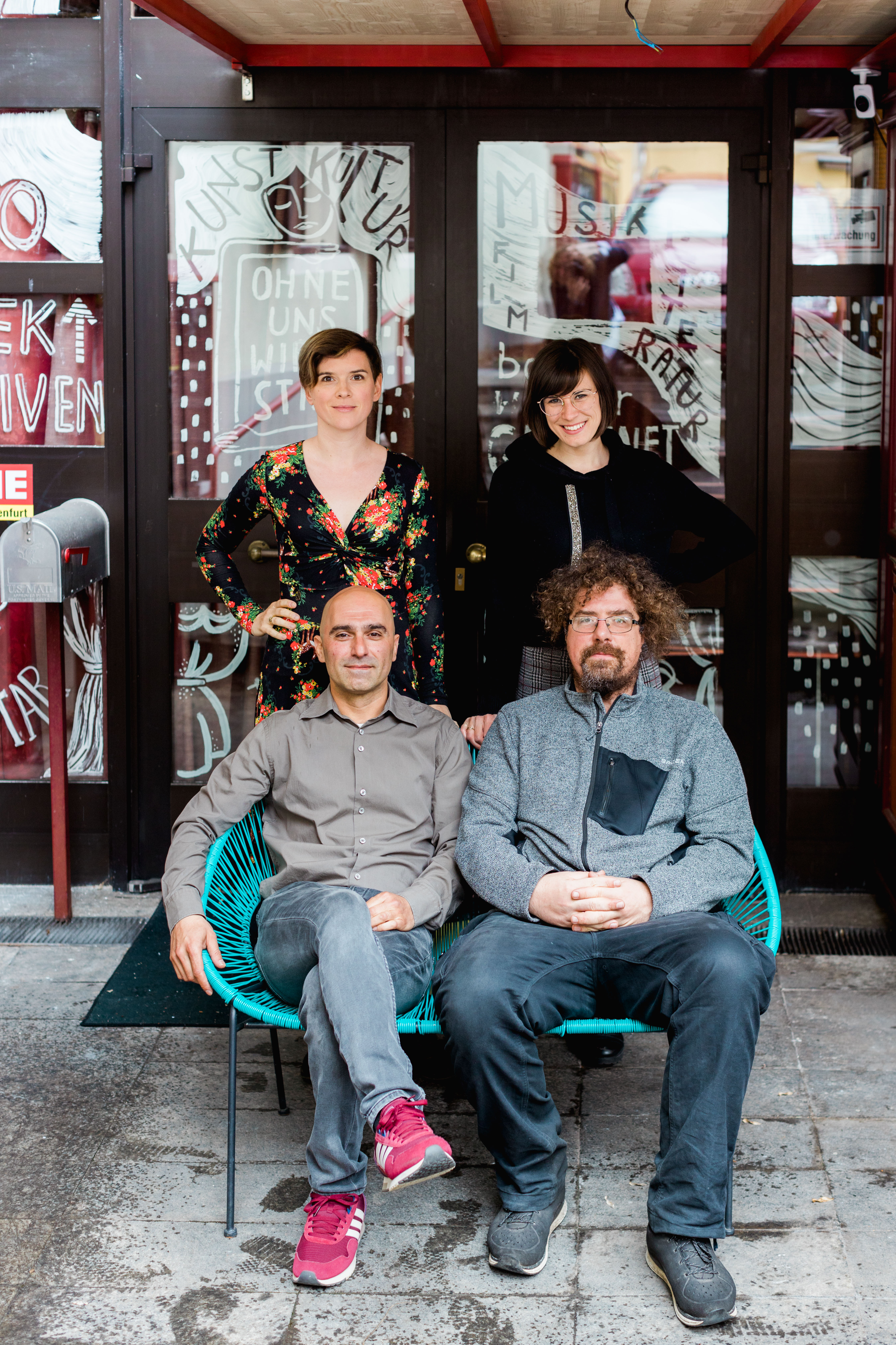 Das Team der Kammerlichtspiele vor dem Haupteingang des Hauses: zwei Männer sitzen auf zwei grünen Stühlen, zwei Frauen stehen hinter ihnen