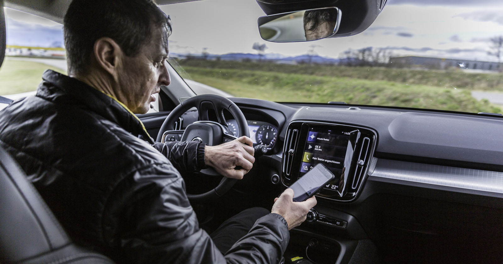 Ein Mann benutzt sein Smartphone während der Autofahrt