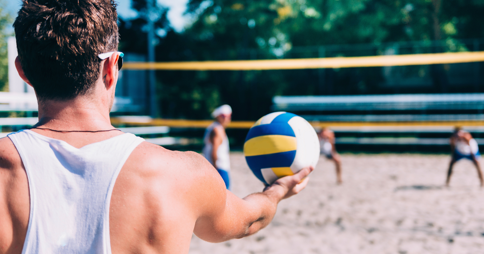 Beachvolleyballspieler schläfgt in weißem Tank-Top auf | Credit: iStock.com/microgen