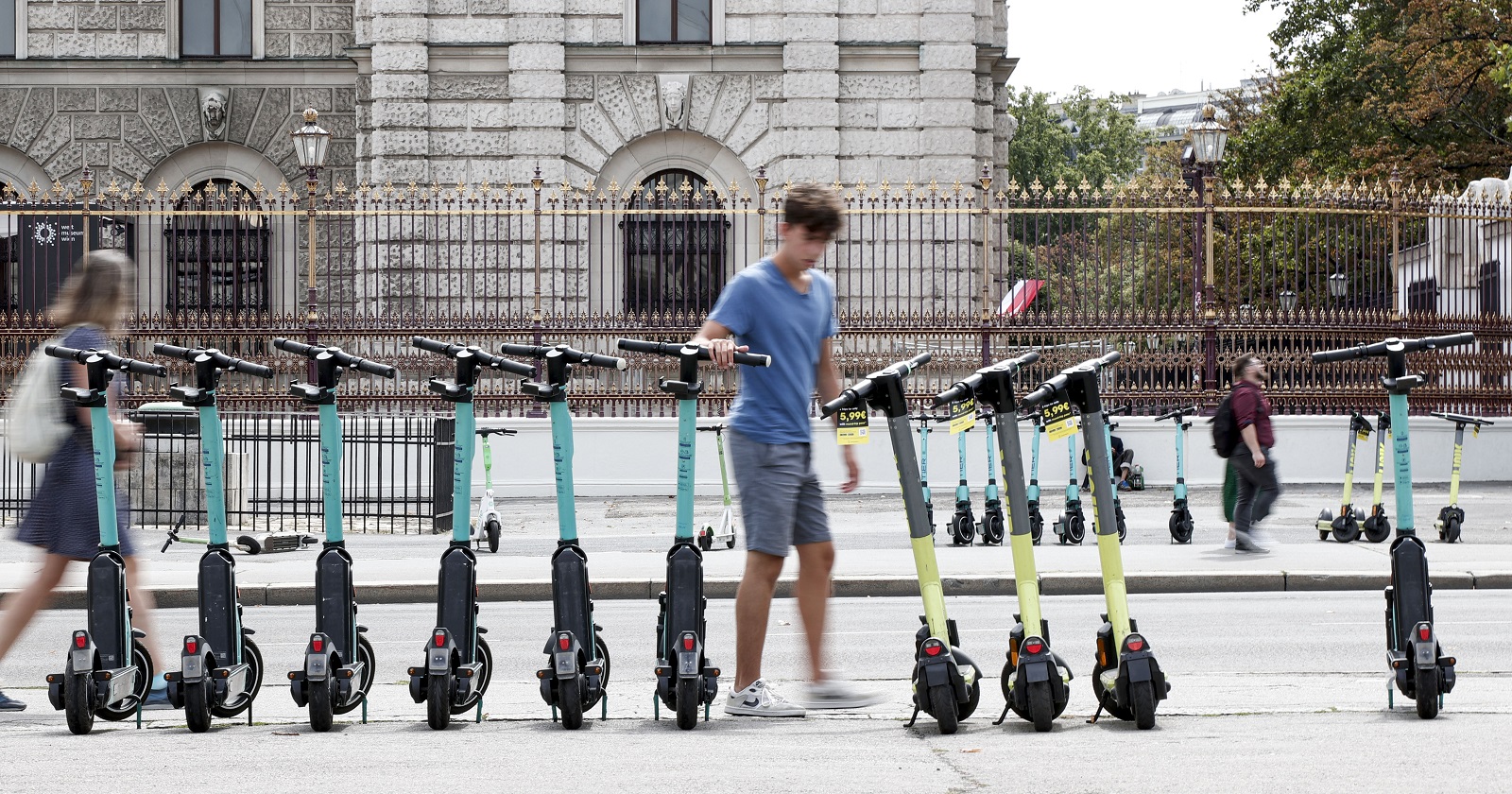 Eine Reihe Leih-E-Scooter, ordentlich nebeneinander abgestellt im Wiener Straßenbild.