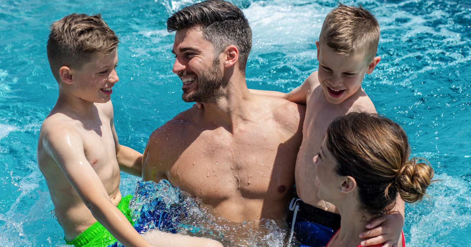 ein Vater steht mit seinem Kindern im Schwimmbecken | Credit: iStock.com/Zoran Zeremski