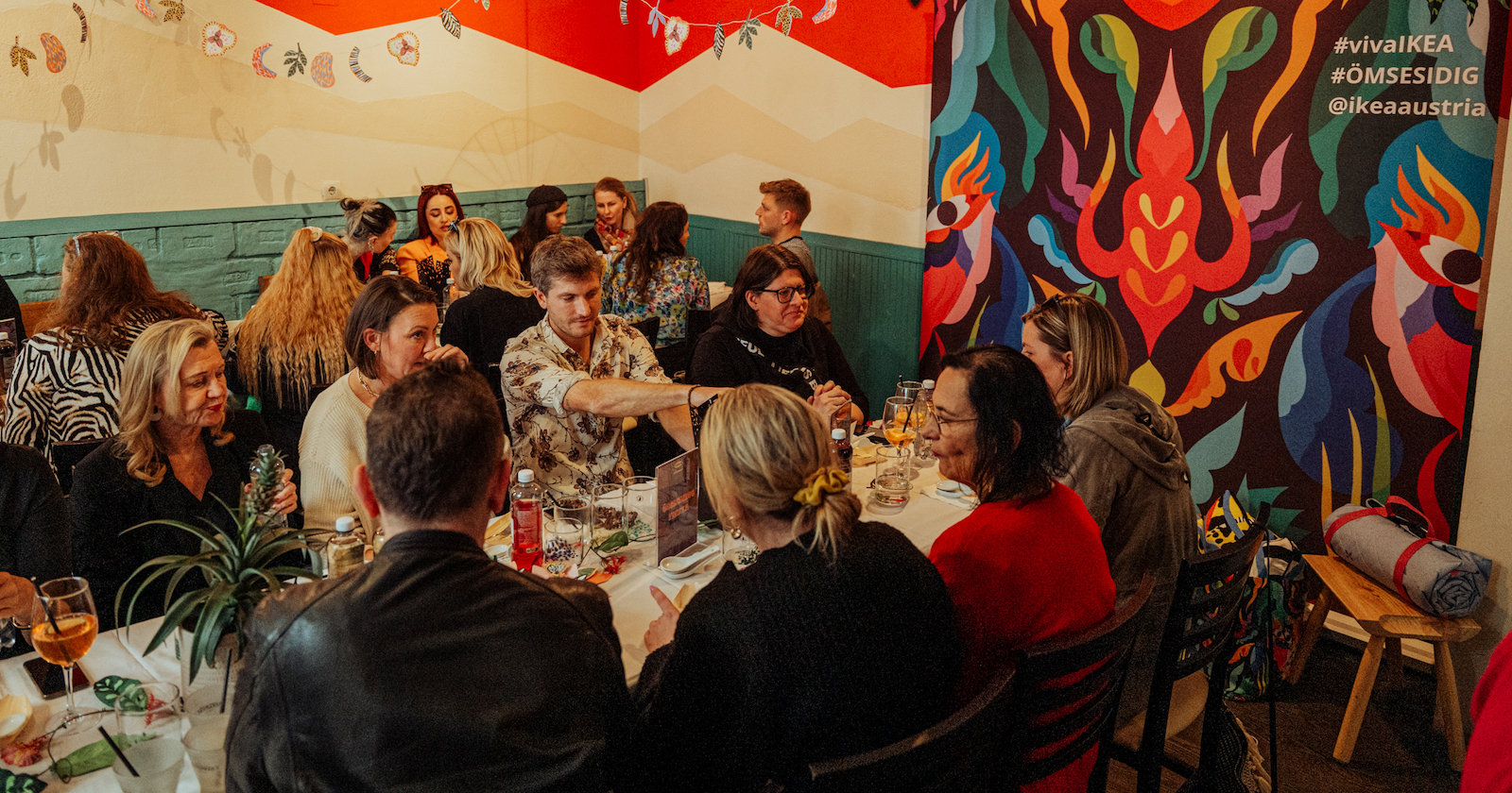 Gäste sitzen in einem peruanischen Restaurant an zwei langen Tischen | Credit: Niklas Stadler/www.niklasstadler.at