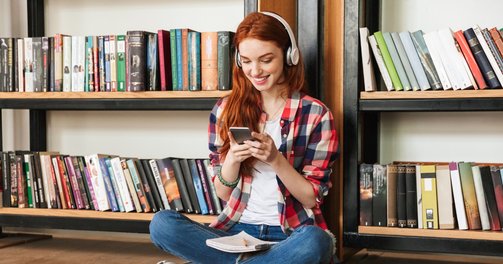 Mädchen sitzt vor einem Bücherregal | Credit: iStock.com/DeanDrobot