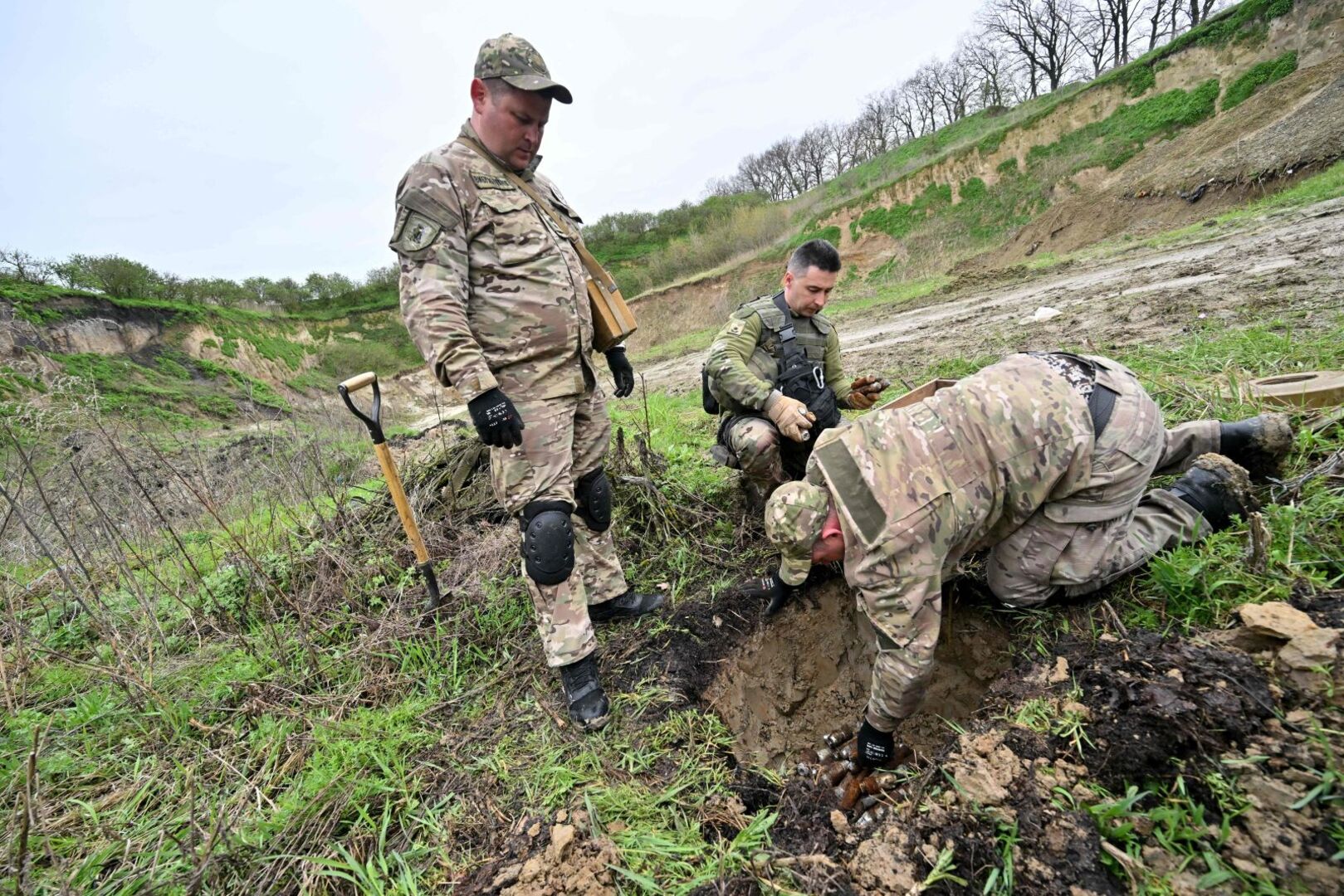 Drei Soldaten entschärfen eine Mine.