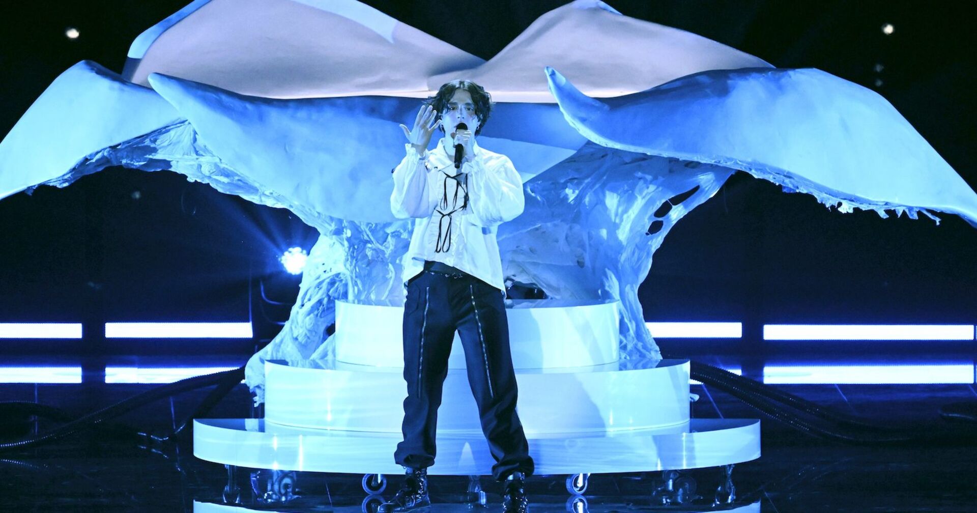 Ein Sänger steht mit Mikro vor einer weißen Skulptur | Credit: Vesa Moilanen / Lehtikuva / picturedesk.com