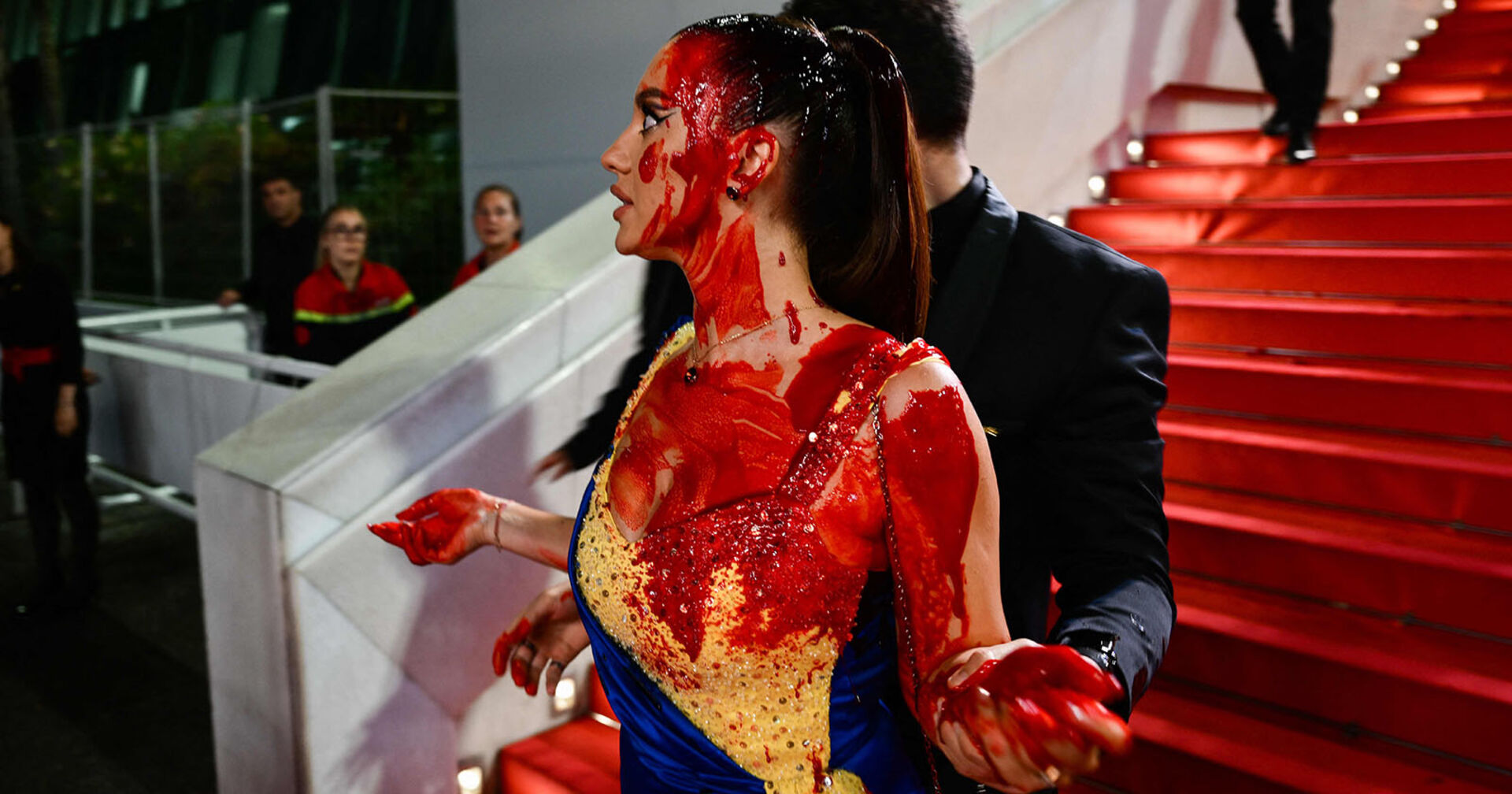 Eine Frau wird in Cannes vom roten Teppich geführt.