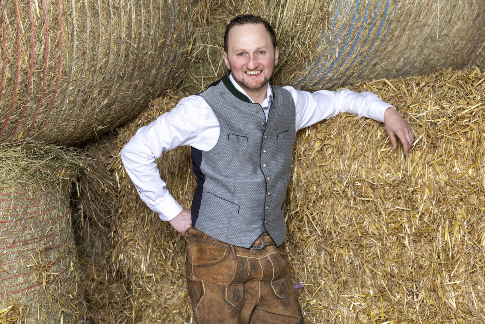 Milchbauer Christoph steht zwischen Heuballen.